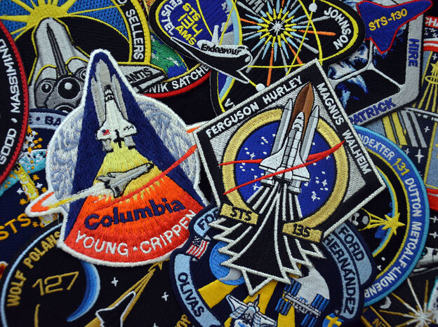 Every space shuttle mission had its own mission emblem, designed and worn by the crews. Centered in this photo are the embroidered patches for the first and last missions, STS-1 and STS-135. The STS-1 emblem is a rare version, produced only for the astronauts and NASA employees. The souvenir edition was slightly different.