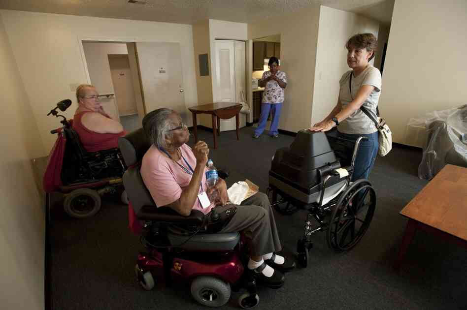 Toni Pastore (right), discusses with Hendrix where to place new furniture in the apartment. The large one-bedroom unit has high ceilings. The building  is a converted school building.