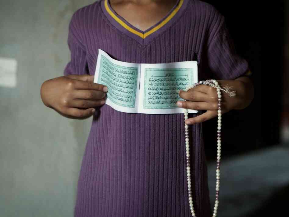 A Zintani family had been living in Tripoli but fled because of violence and instability in the capital. Here, one of the children shows the family's Quran and prayer beads, two of the few possessions they brought with them from Tripoli. A Zintani family had been living in Tripoli but fled because of violence and instability in the capital. Here, one of the children shows the family's Quran and prayer beads, two of the few possessions they brought with them from Tripoli.