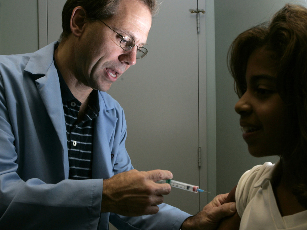 Dr. Donald Brown, left, gives 14-year-old Kelly Kent a dose of Gardasil, a vaccine for the human papillomavirus in 2006. The group that advises the U.S. government on vaccination recommendations is now starting to take costs for vaccines like Gardasil into consideration as vaccine prices rise.