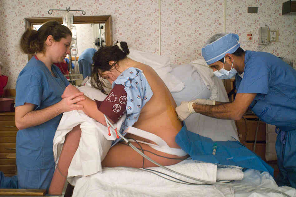 Midwife Magdalene Antill supports Meg Tudryn while a physician inserts an epidural during her delivery at The Birthplace in Greenfield, Mass. Midwife Magdalene Antill supports Meg Tudryn while a physician inserts an epidural during her delivery at The Birthplace in Greenfield, Mass.