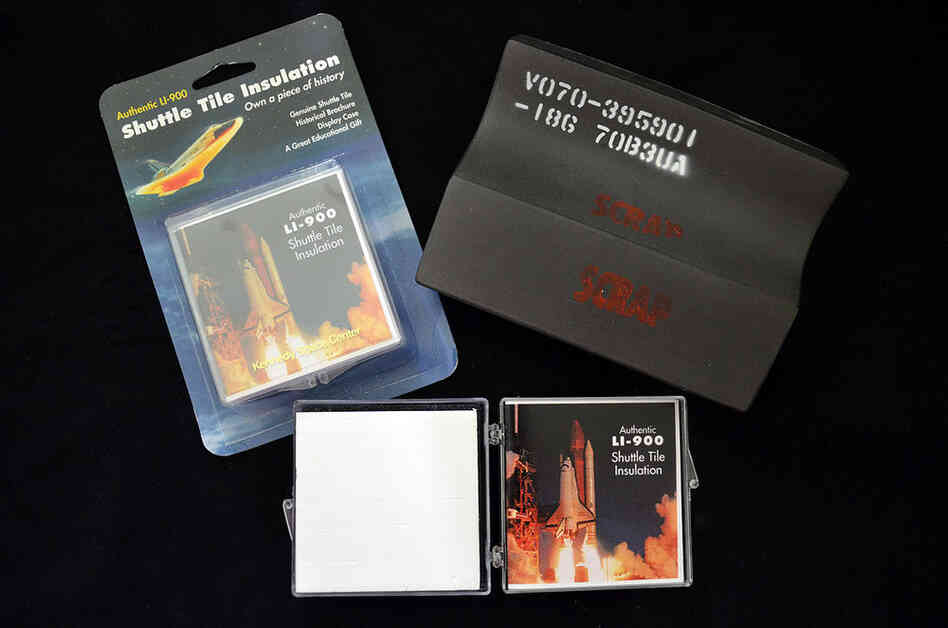Examples of commercial reproductions of space shuttle heat shield tiles alongside a real tile (top right) that was never used. Parts of the space shuttle, or replicas thereof, attract space memorabilia collectors for their rarity and authenticity.