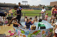 Children keep cool in a swimming pool in right field at Canal Park in Akron, Ohio, on Wednesday.