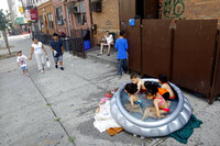 Stephanie Gracia (center) watches as her children and their friends cool off in an inflatable pool outside their apartment Thursday in Brooklyn.