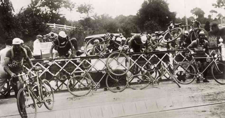 Impatient cyclists climb over the railroad crossing barrier during the 1932 race. That year the tour was shortened by about 357 miles compared to the previous year.