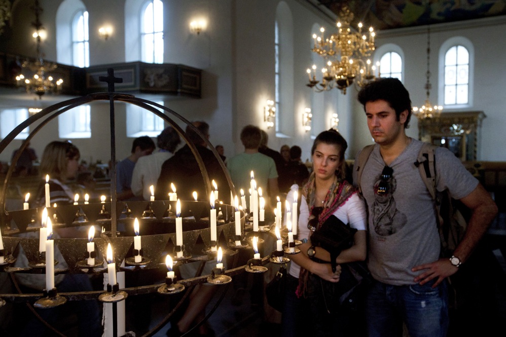 People light candles in Oslo Cathedral on Saturday to pay tribute to the victims of the attacks.  