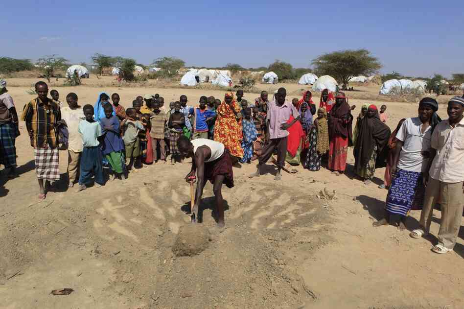 Relatives and friends watch as the final shovelfuls of dusty soil are placed over the grave of 4-year-old Aden Ibrahim, on the outskirts of Ifo 2 camp on July 12. 