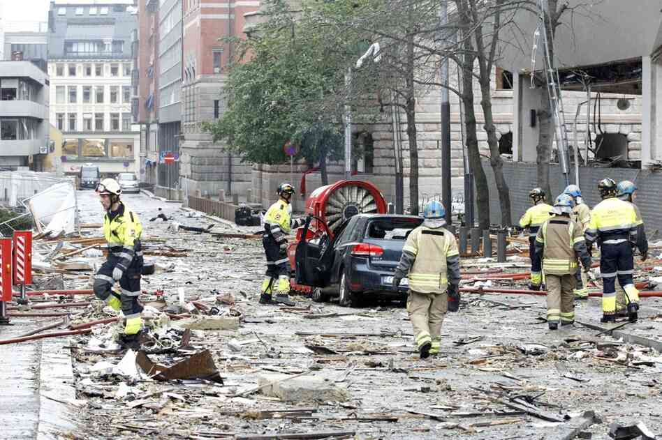 Firefighters work the scene of a debris-filled street near the site of the blast. 