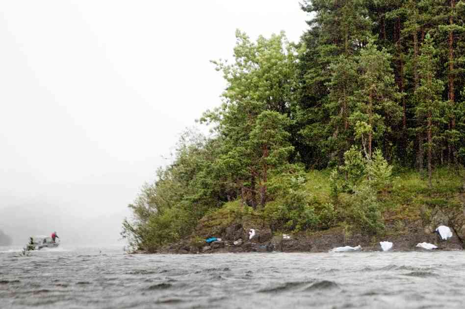 Police and emergency services pass by covered bodies of victims of the attack on the Norwegian Labour Party youth summer camp on Utoya Island, while searching the waters for others on Saturday. Authorities said police also found explosives on the island. 