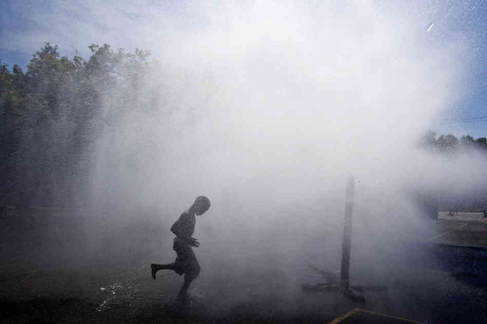 Jayson Hamler runs under a spray of water outside a school on Wednesday in Milwaukee. 