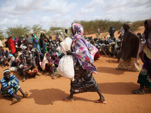 A Somali refugee woman carries a bag of food aid at the entrance to the registration area of the Dadaab refugee settlement in Kenya. While refugees receive international humanitarian aid, local Kenyans fighting drought get sacks of rice, beans and oil from the government. A Somali refugee woman carries a bag of food aid at the entrance to the registration area of the Dadaab refugee settlement in Kenya. While refugees receive international humanitarian aid, local Kenyans fighting drought get sacks of rice, beans and oil from the government.