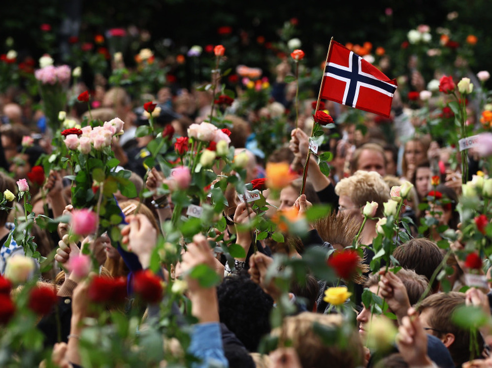 A Norwegian flag is held aloft Monday as people gather in Oslo's town center for a vigil following Friday's twin attacks in Oslo.