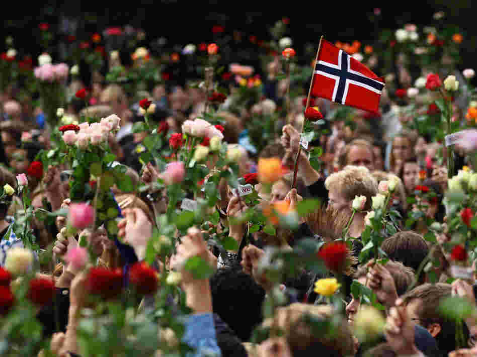 A Norwegian flag is held aloft Monday as people gather in Oslo's town center for a vigil following Friday's twin attacks in Oslo.