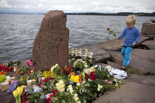 A child walks to place a rose amongst tributes in memory of those killed in the shooting massacre on Utoya island.