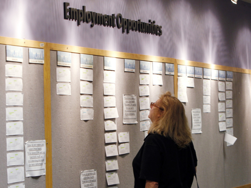 Lori Kamlet looks at posted job opportunities at a Denver employment office last Friday.