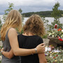 Two young women stood in silence Tuesday after placing flowers at a site off Norway's Utoya island, where a gunman killed at least 68 people.