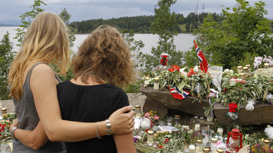 Two young women stood in silence Tuesday after placing flowers at a site off Norway's Utoya island, where a gunman killed at least 68 people.