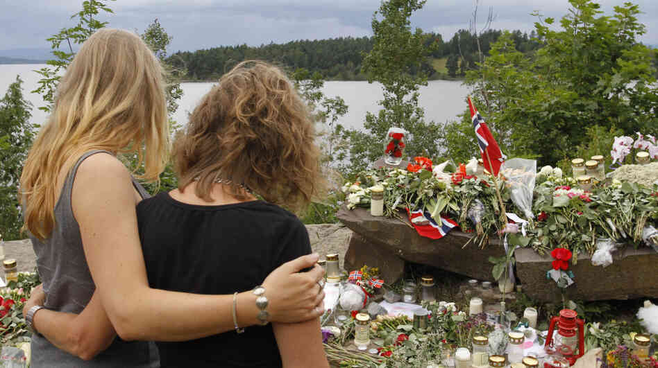 Two young women stood in silence Tuesday after placing flowers at a site off Norway's Utoya island, where a gunman killed at least 68 people.