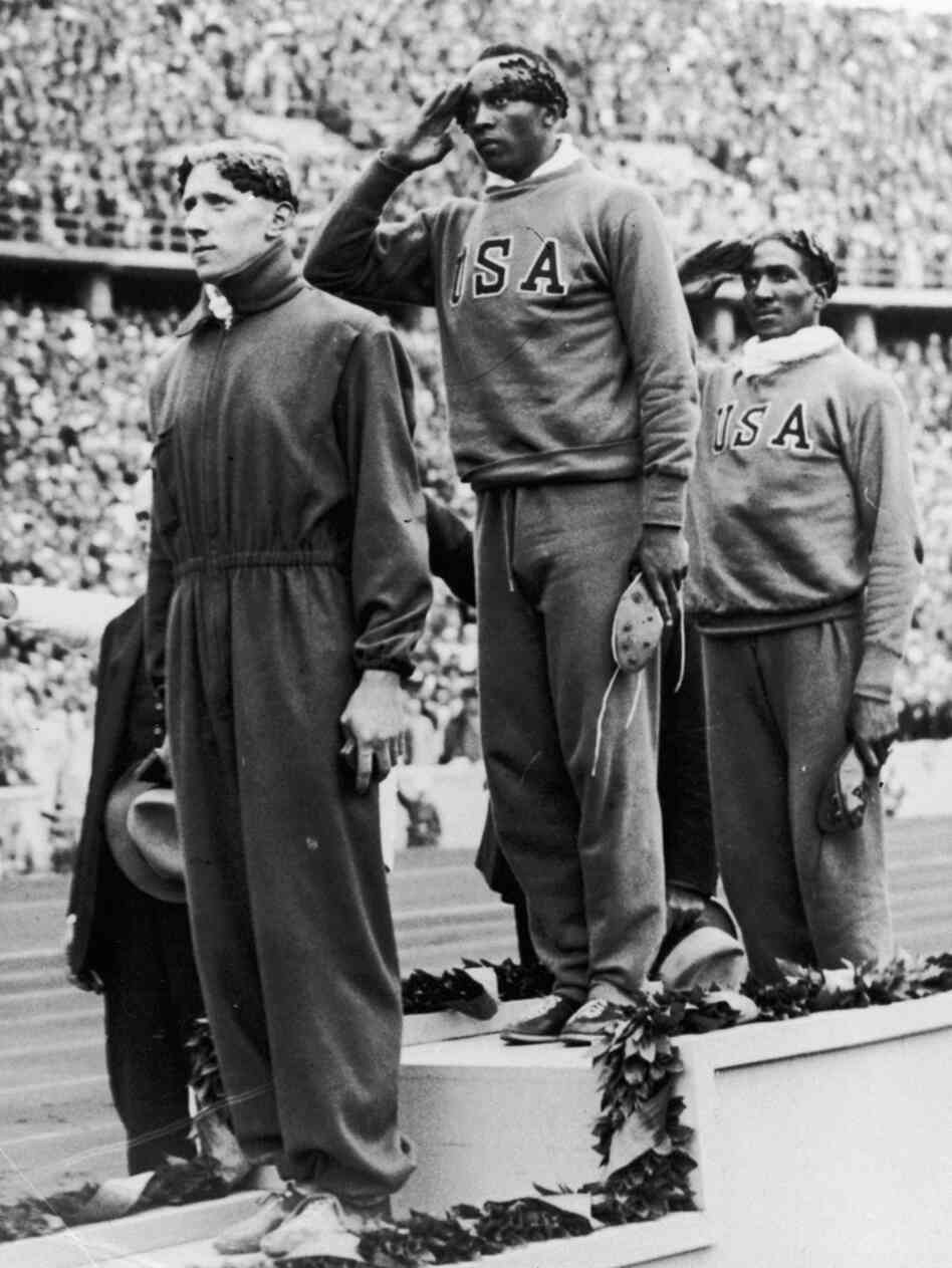 Jesse Owens stands on the podium after winning the gold medal in the 100-meter sprint at the 1936 Berlin Olympic Games. With him are bronze medalist Martinus Osendarp of Holland and silver medalist Ralph Metcalf, also of the U.S. Jesse Owens stands on the podium after winning the gold medal in the 100-meter sprint at the 1936 Berlin Olympic Games. With him are bronze medalist Martinus Osendarp of Holland and silver medalist Ralph Metcalf, also of the U.S.