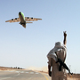 A Libyan rebel fighter flashes a victory sign as an aircraft carrying supplies for the rebels departs along a guarded mile-long stretch of road being used as runway, outside of Rhybat in western Libya, on July 19. A Libyan rebel fighter flashes a victory sign as an aircraft carrying supplies for the rebels departs along a guarded mile-long stretch of road being used as runway, outside of Rhybat in western Libya, on July 19.