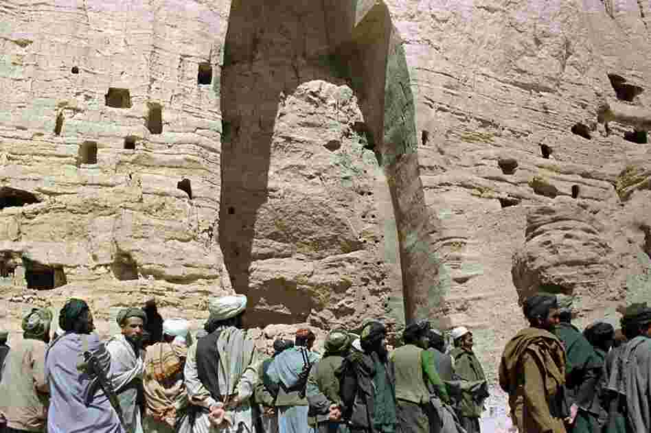 Taliban soldiers stand at the base of a mountain alcove under one of the destroyed Buddha statues in March 2001. 