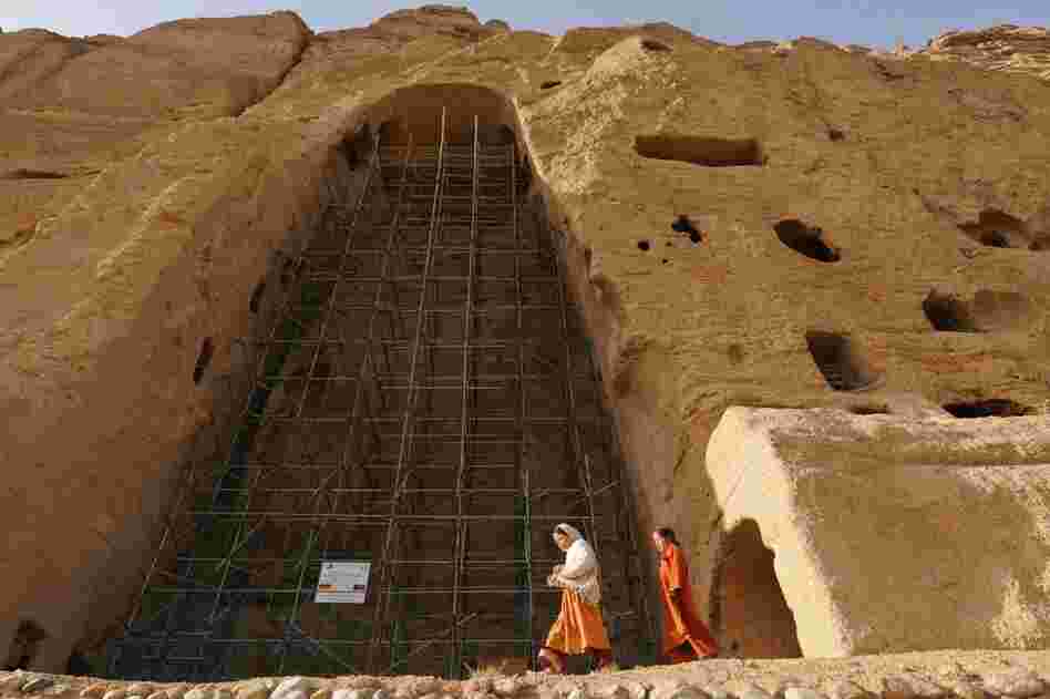 Afghan girls walk past scaffolding at the site of one of the destroyed Buddha statues in this 2008 photo. Some Bamiyan residents support the restoration project. Others say the statues should not be rebuilt, to remind people of the Taliban's fanaticism. 