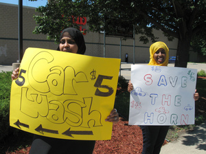 Iman Warsame (left) and Fardosa Ahmed drum up business for their car wash; proceeds from the event (below) went to help drought victims in Somalia. Iman Warsame (left) and Fardosa Ahmed drum up business for their car wash; proceeds from the event (below) went to help drought victims in Somalia.