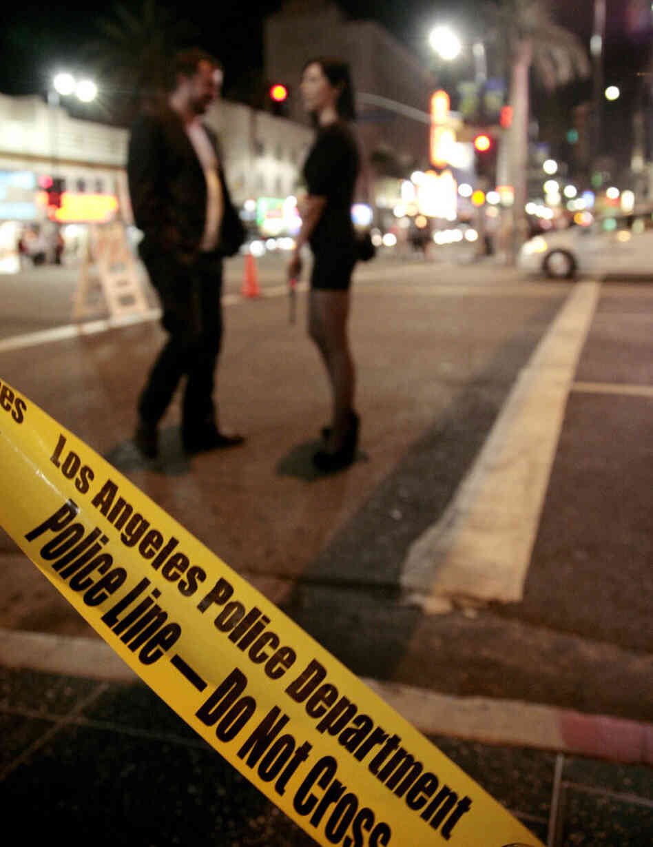 A couple waits at the intersection of Hollywood Boulevard and Highland Avenue after an unruly crowd trying to attend an Electric Daisy Carnival concert film threw rocks and bottles at police cars in Los Angeles.