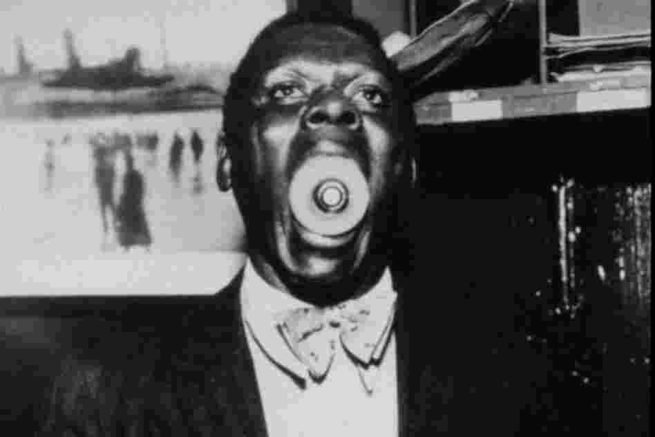 A man holds the large end of a light bulb inside his mouth, with the metal input facing the camera.