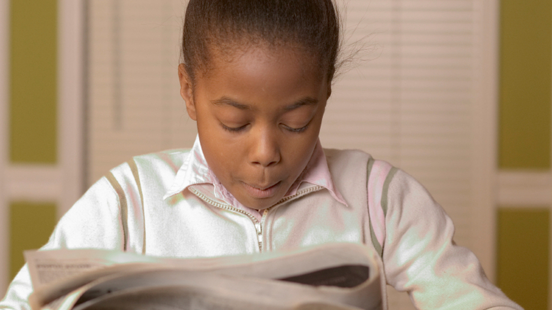 Young girl reading the newspaper.