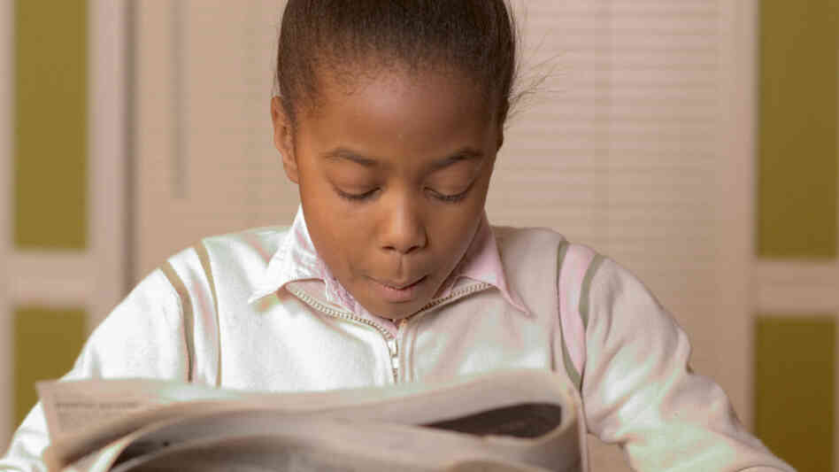 Young girl reading the newspaper.