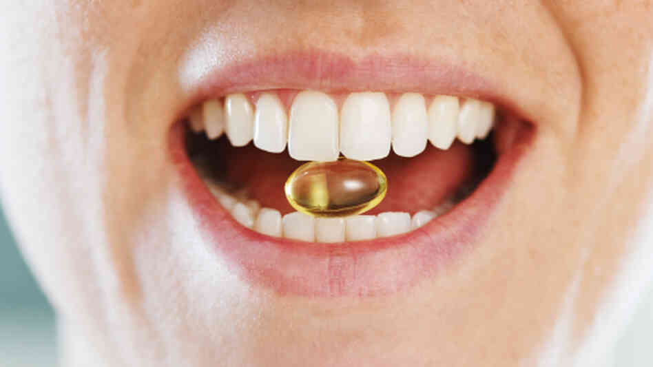 Closeup of woman holding a capsule between her teeth.. Closeup of woman holding a capsule between her teeth..