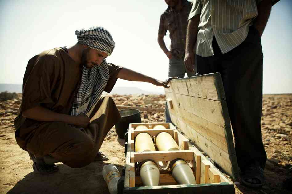 A rebel looks at a crate containing two 100mm rounds for the main gun of a T-55 battle tank that had previously belonged to Moammar Gadhafi's forces.