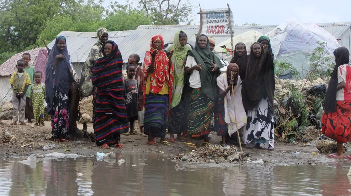 Women from southern Somalia stand  near pooled rainwater in Mogadishu, Somalia, Monday, Aug 1, 2011. Tens of thousands of famine-stricken Somali refugees were cold and drenched after torrential rains overnight pounded their makeshift structures in the capital, Mogadishu.