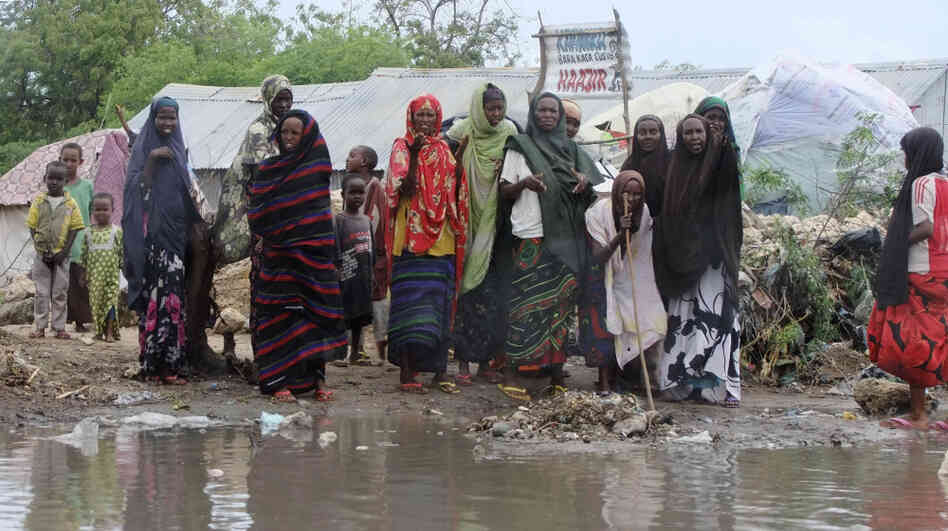 Women from southern Somalia stand  near pooled rainwater in Mogadishu, Somalia, Monday, Aug 1, 2011. Tens of thousands of famine-stricken Somali refugees were cold and drenched after torrential rains overnight pounded their makeshift structures in the capital, Mogadishu.