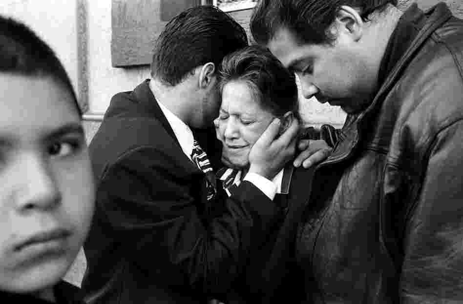 Chi Chi's mother and brothers cry at his funeral. Chi Chi, an innocent bystander, was murdered during a hit on a drug dealer,  1990s.