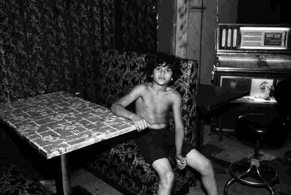 Boy sits at table in adult social club, 1980s