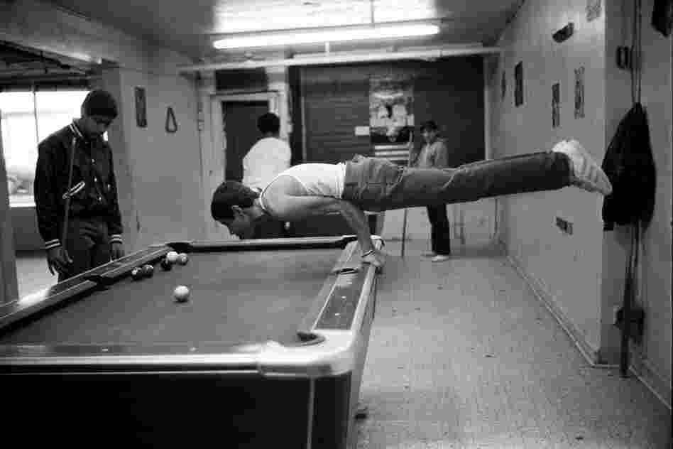 Martin, a teenager, shows his muscles by doing a pushup on the pool table, 1980s.