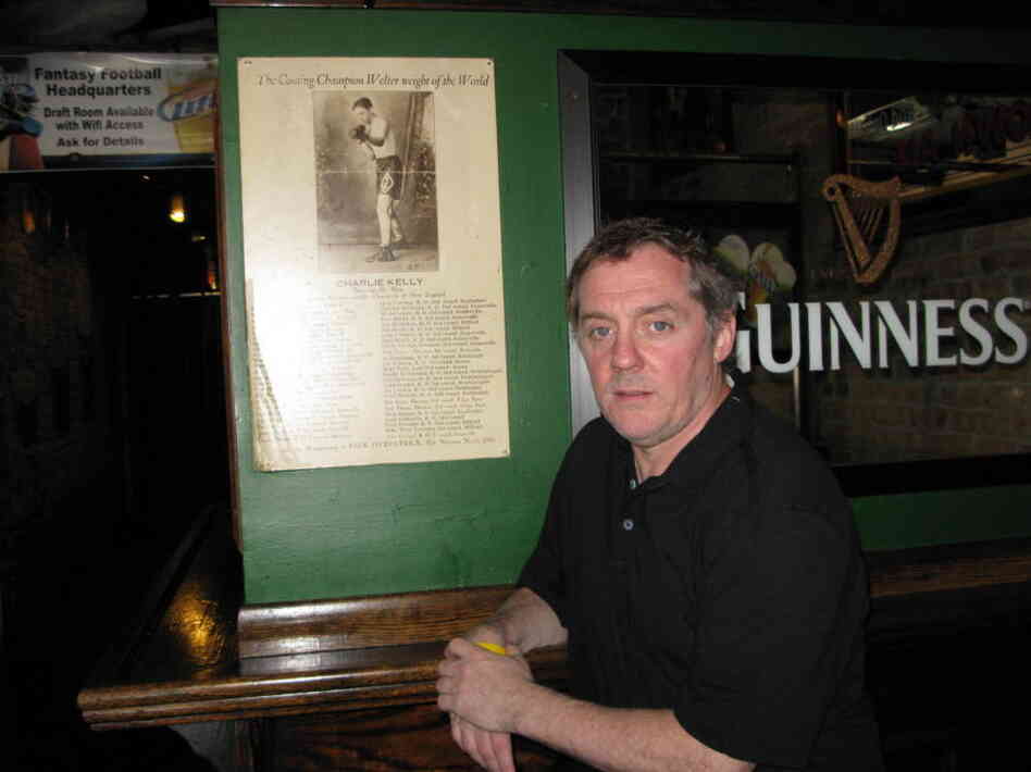 Michael Harvey stands next to a poster of his great-great-uncle Charlie Kelly at his Lincoln Park bar. Harvey's main character, Michael Kelly, was named after Charlie's father.