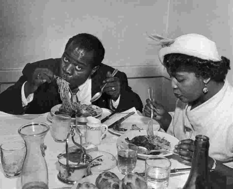 Louis Armstrong tucks into a plate of spaghetti in Rome with his wife Lucille in 1949.