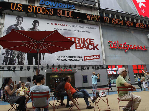 People sit beneath a news ticker in Times Square Thursday, Aug. 4, 2011  in New York. Gripped by fear of another recession, the financial markets suffered their worst day Thursday since the crisis of 2008. The Dow Jones industrial average fell more than 500 points, its ninth-steepest decline ever.