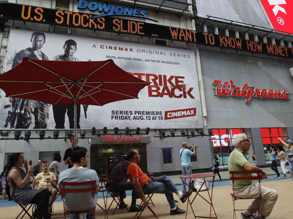 People sit beneath a news ticker in Times Square Thursday, Aug. 4, 2011  in New York. Gripped by fear of another recession, the financial markets suffered their worst day Thursday since the crisis of 2008. The Dow Jones industrial average fell more than 500 points, its ninth-steepest decline ever.