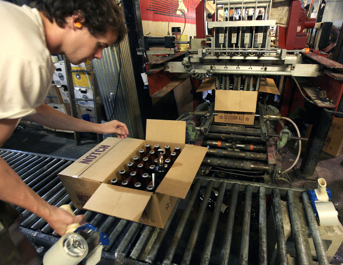 Cellarman Cooper Reid packs cases of beer at the Ipswich Ale Brewery in July. New rules put out by the state's alcohol commission require "farmer-brewers" like Ipswich to grow 50 percent of their own grains and hops, or get it from domestic farms.