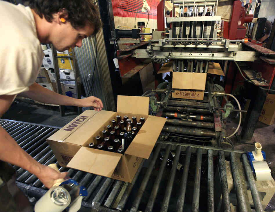 Cellarman Cooper Reid packs cases of beer at the Ipswich Ale Brewery in July. New rules put out by the state's alcohol commission require "farmer-brewers" like Ipswich to grow 50 percent of their own grains and hops, or get it from domestic farms.