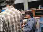 KAZU's Production Assistant Andrew Kramer shows Caetano around the control room.