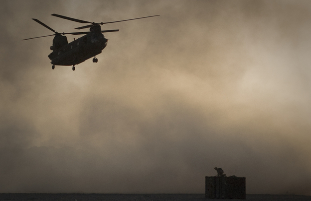 A U.S. Marine tries to take cover as a Chinook helicopter arrives at Forward Operating Base Edi in the Helmand Province of southern Afghanistan, Thirty Americans were killed when a helicopter crashed in eastern Wardak province early Saturday.