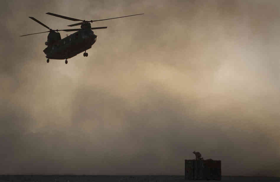 A U.S. Marine tries to take cover as a Chinook helicopter arrives at Forward Operating Base Edi in the Helmand Province of southern Afghanistan, Thirty Americans were killed when a helicopter crashed in eastern Wardak province early Saturday.