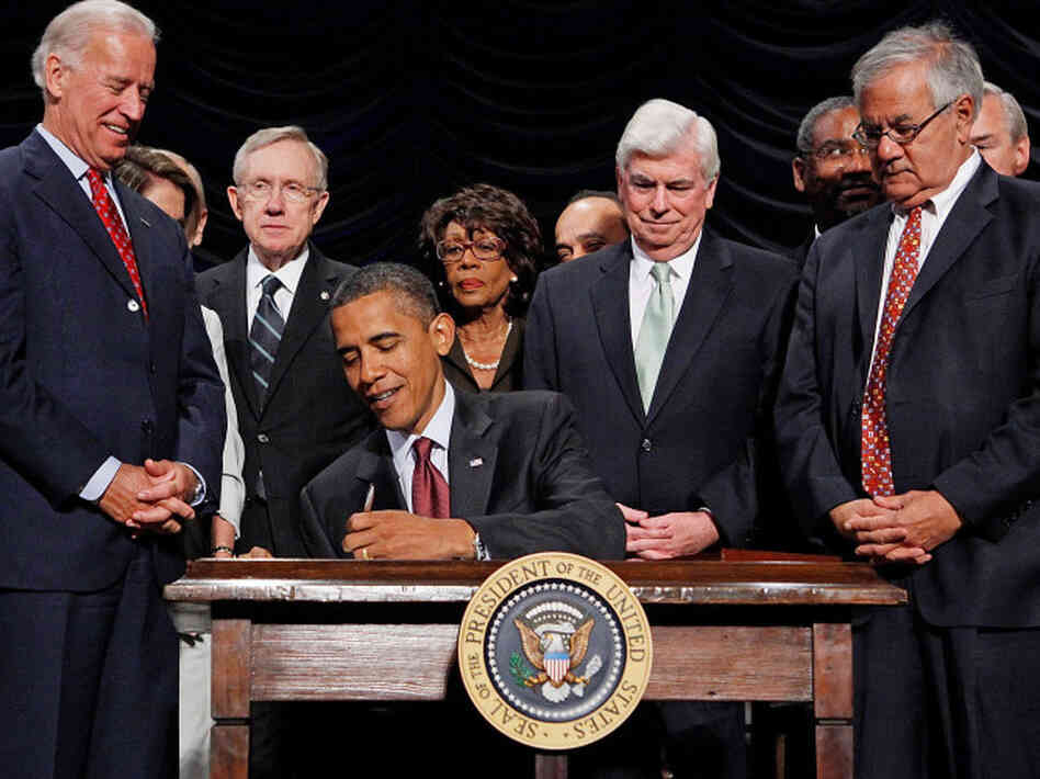 President Obama signs the financial reform bill into law in 2010 as Vice President Biden and lawmakers look on.