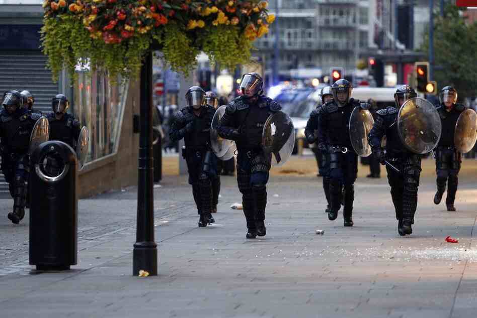 Riot police patrol the street in Manchester on Aug 9. Britain began flooding London's streets with 16,000 police officers, nearly tripling their presence, to combat the worst rioting in a generation. 