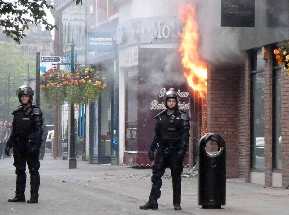 Fire rips through a retail store in Manchester, in northwest England, Tuesday, marking a fourth night of violence in Britain. Looters have targeted electronics and clothing stores.